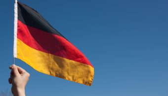 Hand is holding the germany flag against blue sky